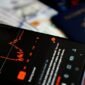 Seorang investor tersenyum sembari melihat grafik pertumbuhan dividen di aplikasi investasi, menggambarkan kegembiraan saat menerima aliran dana tunai dari keuntungan perusahaan. Pemandangan ini merefleksikan optimisme pasar modal terhadap musim panen dividen yang sedang berlangsung.