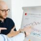 Ilustrasi sertifikat obligasi konversi dengan grafik pasar saham di latar belakang, menunjukkan kompleksitas dan potensi dinamika instrumen keuangan ini. Gambar ini merepresentasikan peluang serta tantangan yang dihadapi investor dalam memahami dan memanfaatkan obligasi konversi sebagai bagian dari strategi investasi mereka.
