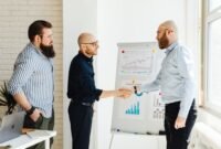 Dua pebisnis berjabat tangan di depan grafik pertumbuhan yang melambangkan keberhasilan merger, menunjukkan sinergi dan optimisme terhadap masa depan yang lebih kuat. Integrasi strategis ini bertujuan menciptakan entitas bisnis yang lebih besar dan berdaya saing di tengah dinamika ekonomi.