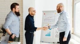 Dua pebisnis berjabat tangan di depan grafik pertumbuhan yang melambangkan keberhasilan merger, menunjukkan sinergi dan optimisme terhadap masa depan yang lebih kuat. Integrasi strategis ini bertujuan menciptakan entitas bisnis yang lebih besar dan berdaya saing di tengah dinamika ekonomi.