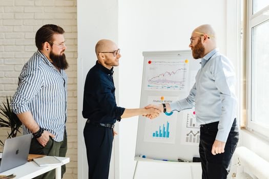 Dua pebisnis berjabat tangan di depan grafik pertumbuhan yang melambangkan keberhasilan merger, menunjukkan sinergi dan optimisme terhadap masa depan yang lebih kuat. Integrasi strategis ini bertujuan menciptakan entitas bisnis yang lebih besar dan berdaya saing di tengah dinamika ekonomi.