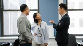 Tim karyawan sedang berdiskusi di sebuah ruang rapat modern, menunjukkan kolaborasi dalam menghadapi perubahan struktur perusahaan. Mereka terlihat fokus dan proaktif, mencerminkan semangat adaptasi dalam lingkungan kerja yang dinamis.