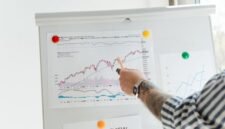 Ilustrasi grafik saham dengan panah ke atas dan seseorang memegang sertifikat saham, merefleksikan dinamika keputusan right issue di pasar modal. Foto ini menggambarkan bagaimana strategi keuangan korporasi memengaruhi pergerakan investasi dan portofolio para pemegang saham.
