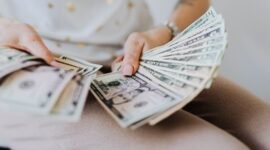 Tangan memegang tumpukan uang tunai, menggambarkan aliran dana dividen yang mengalir langsung ke tangan investor, sebagai bentuk keuntungan dari kepemilikan saham perusahaan. Momen ini menjadi tanda positif bagi kesehatan finansial perusahaan dan hadiah bagi kesabaran investor.
