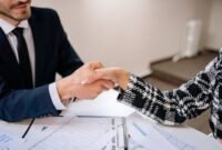 Dua eksekutif berjabat tangan di depan gedung pencakar langit modern, melambangkan momen krusial persetujuan akuisisi perusahaan. Gambar ini merefleksikan dinamika akuisisi yang seringkali mengubah lanskap bisnis secara signifikan.