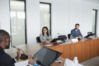 Suasana serius dalam sebuah rapat pemegang saham yang sedang berlangsung, di mana para petinggi perusahaan dan pemilik modal berdiskusi mengenai arah strategis bisnis di masa mendatang. Ruangan formal ini menjadi saksi bisu keputusan penting yang akan memengaruhi ribuan karyawan dan operasional perusahaan secara global.