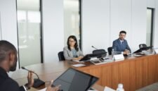 Suasana serius dalam sebuah rapat pemegang saham yang sedang berlangsung, di mana para petinggi perusahaan dan pemilik modal berdiskusi mengenai arah strategis bisnis di masa mendatang. Ruangan formal ini menjadi saksi bisu keputusan penting yang akan memengaruhi ribuan karyawan dan operasional perusahaan secara global.