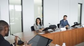 Suasana serius dalam sebuah rapat pemegang saham yang sedang berlangsung, di mana para petinggi perusahaan dan pemilik modal berdiskusi mengenai arah strategis bisnis di masa mendatang. Ruangan formal ini menjadi saksi bisu keputusan penting yang akan memengaruhi ribuan karyawan dan operasional perusahaan secara global.