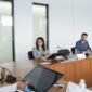 Suasana serius dalam sebuah rapat pemegang saham yang sedang berlangsung, di mana para petinggi perusahaan dan pemilik modal berdiskusi mengenai arah strategis bisnis di masa mendatang. Ruangan formal ini menjadi saksi bisu keputusan penting yang akan memengaruhi ribuan karyawan dan operasional perusahaan secara global.