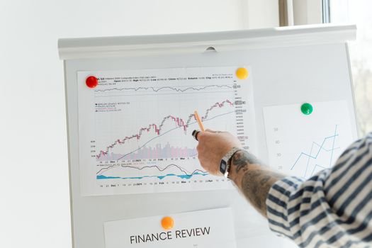 Ilustrasi seorang pebisnis dengan latar belakang grafik saham menunjukkan konsep buyback saham, di mana perusahaan membeli kembali sahamnya dari pasar untuk berbagai tujuan strategis. Langkah ini sering dilakukan untuk mengelola struktur modal dan meningkatkan nilai bagi pemegang saham.