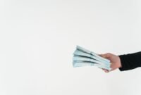 Seorang investor tersenyum saat memegang lembaran uang, melambangkan kegembiraan menerima dividen tunai dari investasi sahamnya. Momen ini seringkali menjadi puncak kebahagiaan bagi mereka yang telah menanam modal dengan bijak di pasar saham.